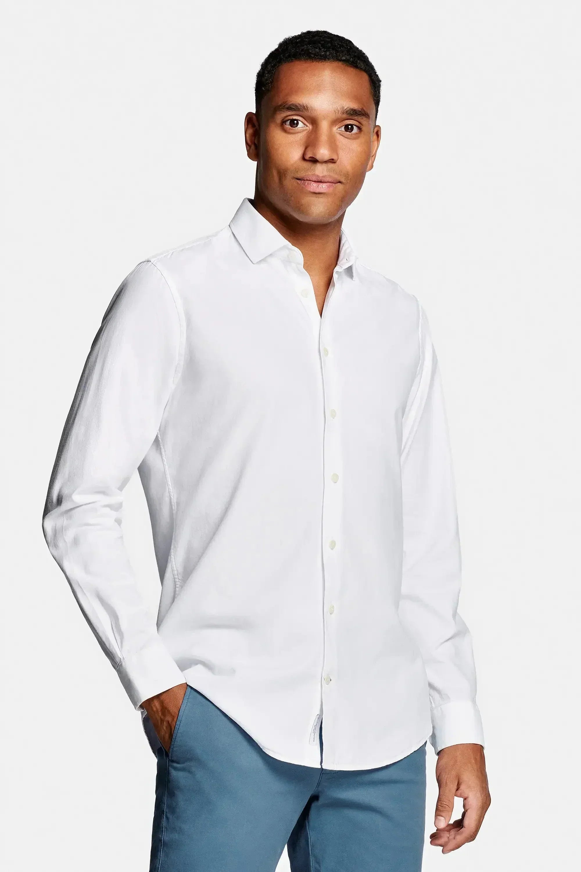 White cotton chemise by Emiral Couture, featuring a classic collar and button-down front, elegantly draped on a hanger.